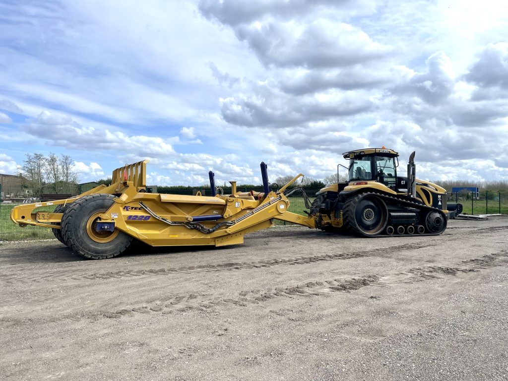 IMG_2371-1024×768 Large yellow Caterpillar tracked tractor pulling a heavy-duty land scraper on a construction site.