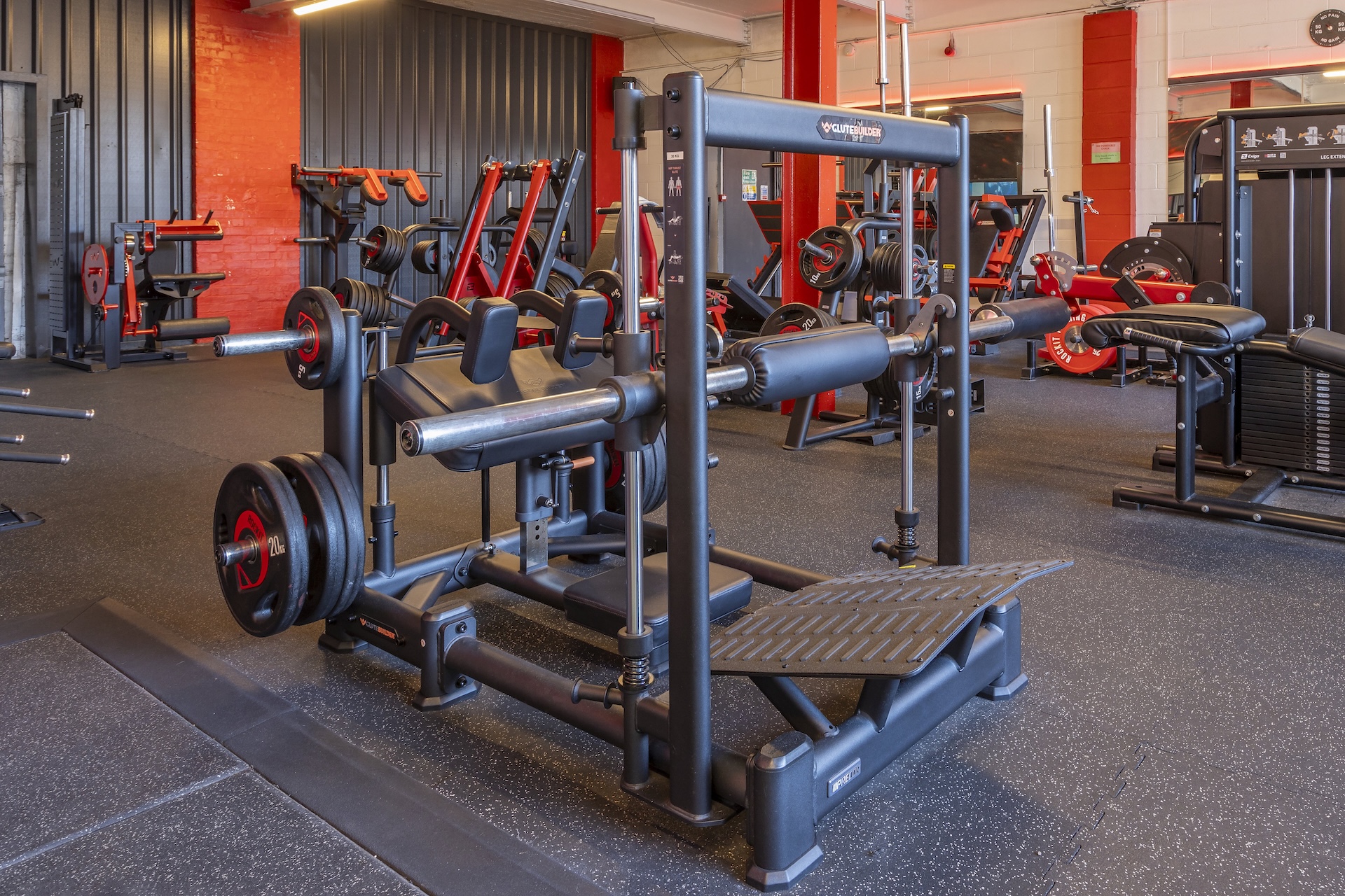 Close-up of leg press equipment in a gym with red and black weight machines.