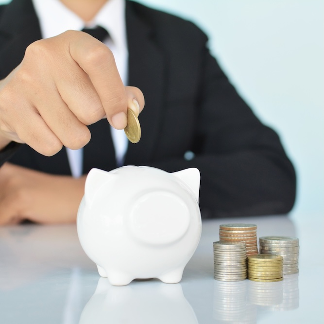 Business man holding coin and white piggy bank on blue background selective and soft focus